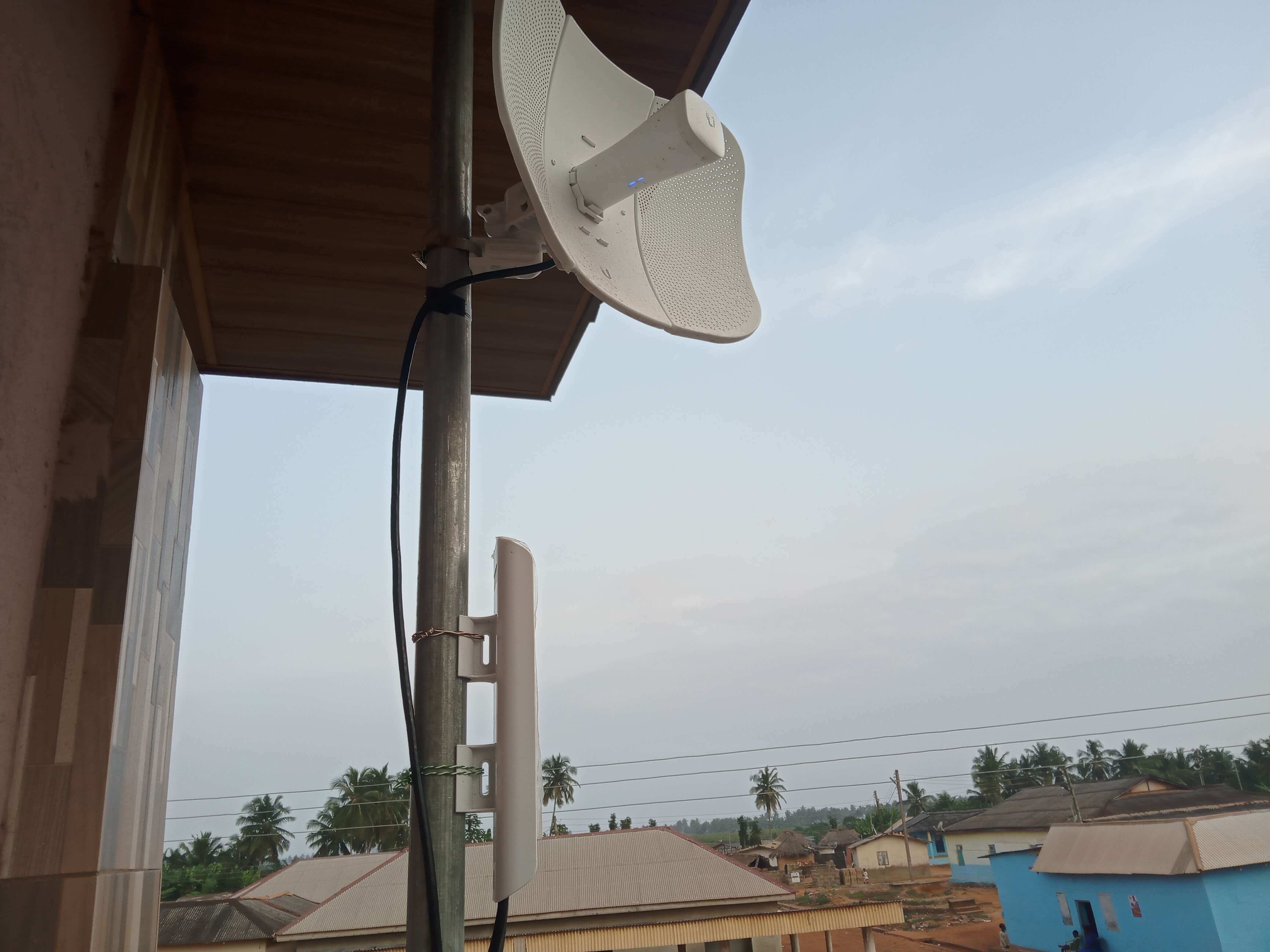 Relay antenna mounted under a roof overlooking Kuntu village